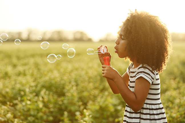 Little African American Girl Blowing Bubbles In Field; Shutterstock ID 500147458; CUID: 030250; Organization Name: Fort Worth Community CU; Usage (Sales, Marketing, Internal, Other): Marketing